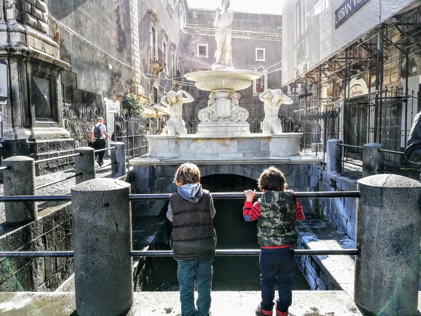 dei bambini che guardano la fontana dell'Amenano a Catania